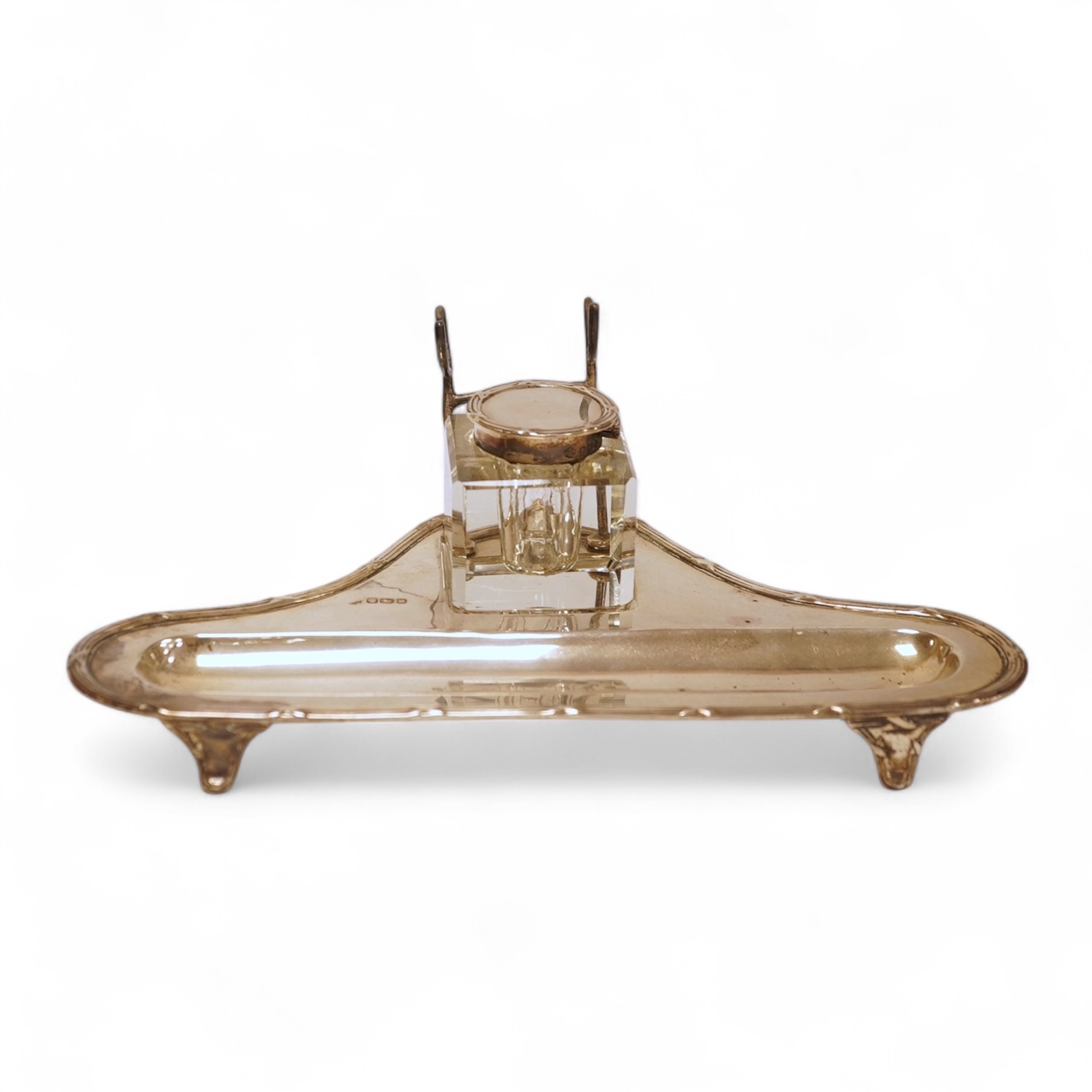 A George V silver inkstand, with single mounted glass well, pen rest and pen recess, with reeded ribbon border, William Hutton & Sons, Sheffield, 1913, 23.9cm, 5.2oz.
